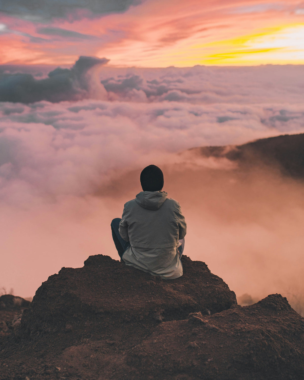 A calm person, in the mountains, above the clouds, feeling a sense of peace looking above it all.